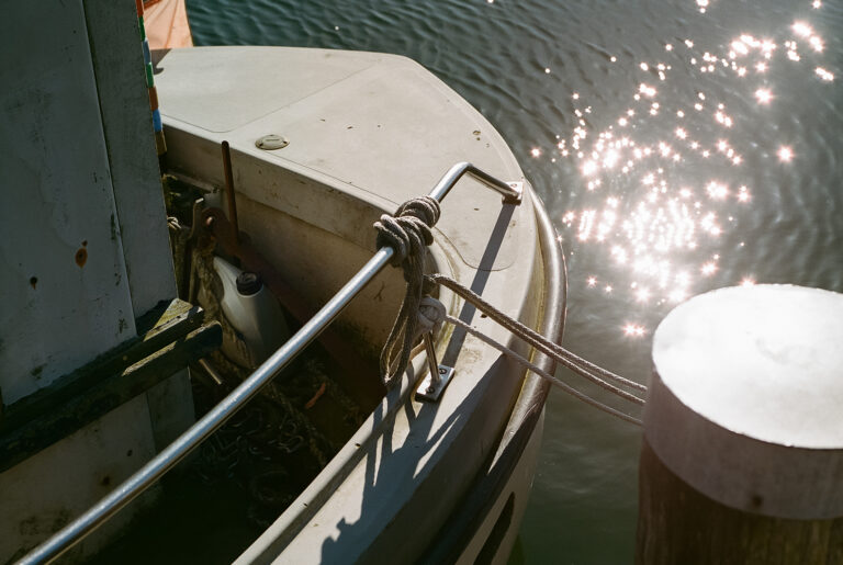 Analoges Foto eines Bootes im Hafen von Poel. Geschossen mit der Mamiya 645. Sonne glitzert in der Ostsee.